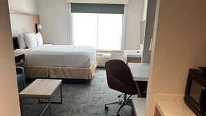 A hotel room with a bed, desk, chair, and kitchenette. - Wingate by Wyndham Richmond Short Pump (Richmond)