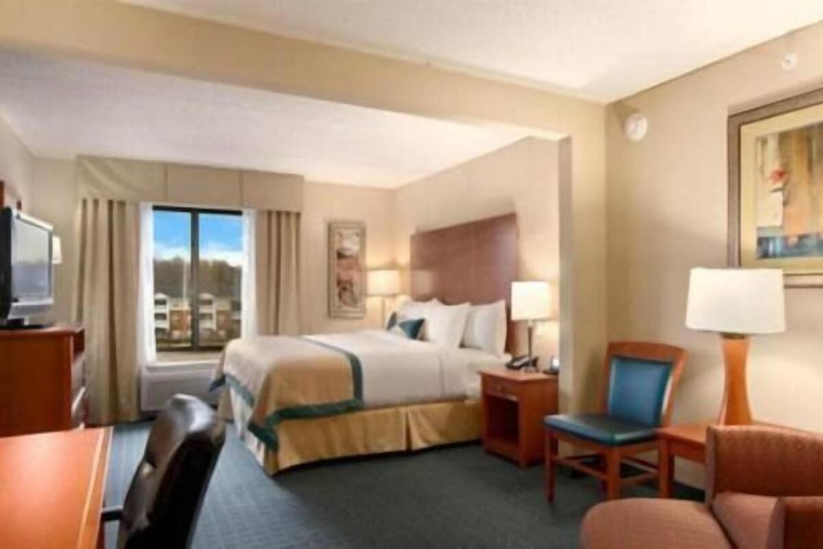 Ein Hotelzimmer mit Bett, Schreibtisch, Stuhl, Fernseher und Fenster.