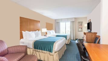 A hotel room with two beds, a desk, a chair, and a television.