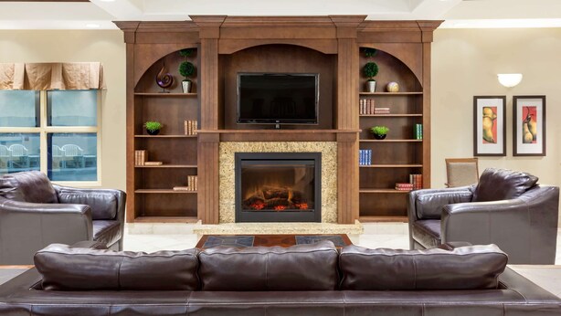 Una sala de estar con chimenea, sofás de cuero y un televisor sobre la chimenea.