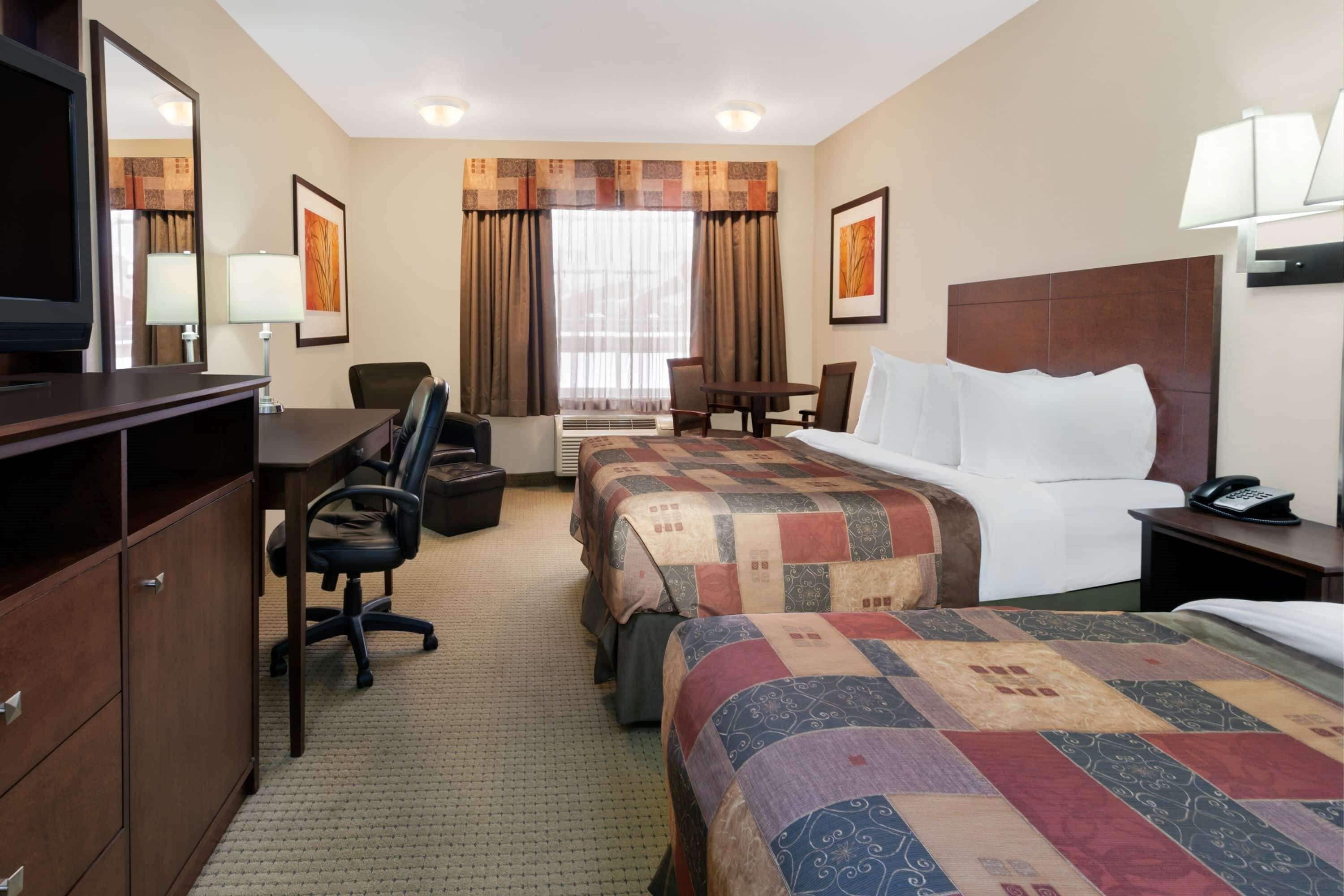 Una habitación de hotel con una cama grande, un escritorio con silla, un televisor y un armario.