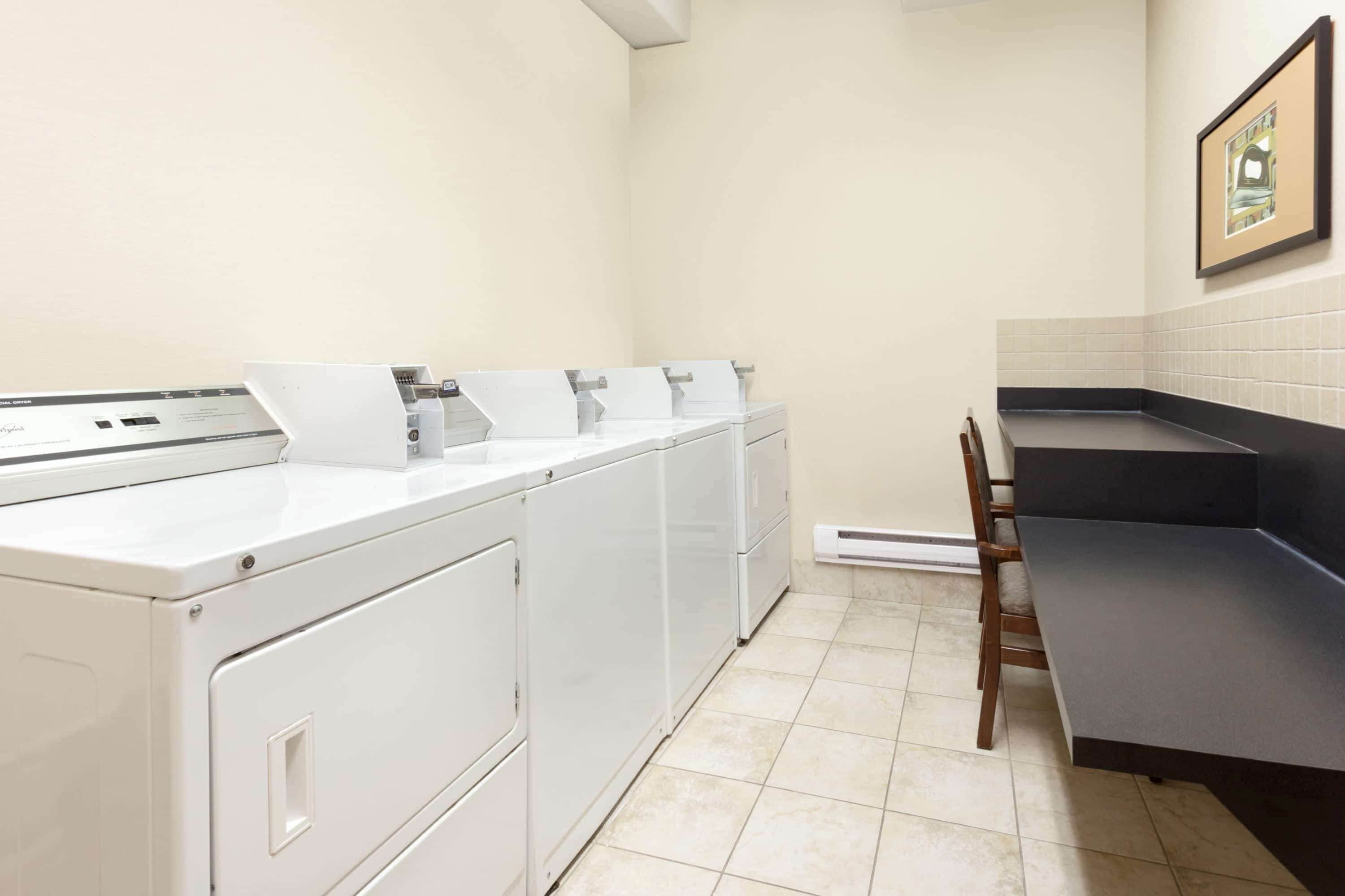 A laundry area with a washing machine, dryer, and a bench.