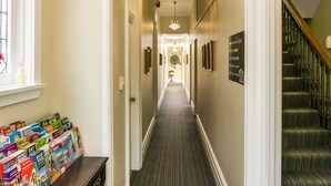 A hallway with a wooden bench, a chandelier, and a staircase.