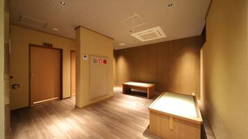 A hallway with wooden flooring, a bench, and a desk.