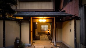 A traditional Japanese entrance with a stone pathway leading to a wooden gate.