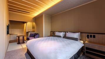 A modern hotel room with a large bed, a desk, a chair, and a small table.