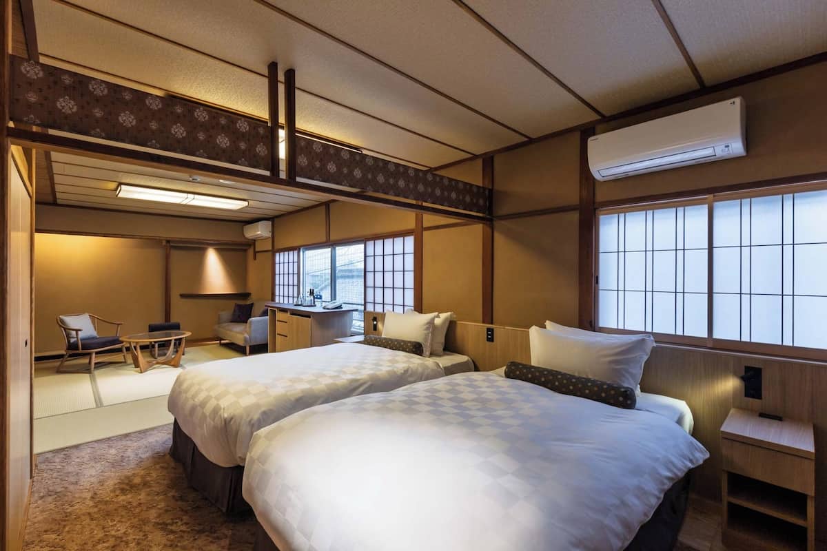 A traditional Japanese-style room with two beds, a desk, and a chair.