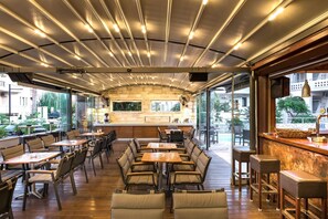An indoor seating area with tables and chairs, a bar counter, and a stone wall. - Elotis Suites (Chania)