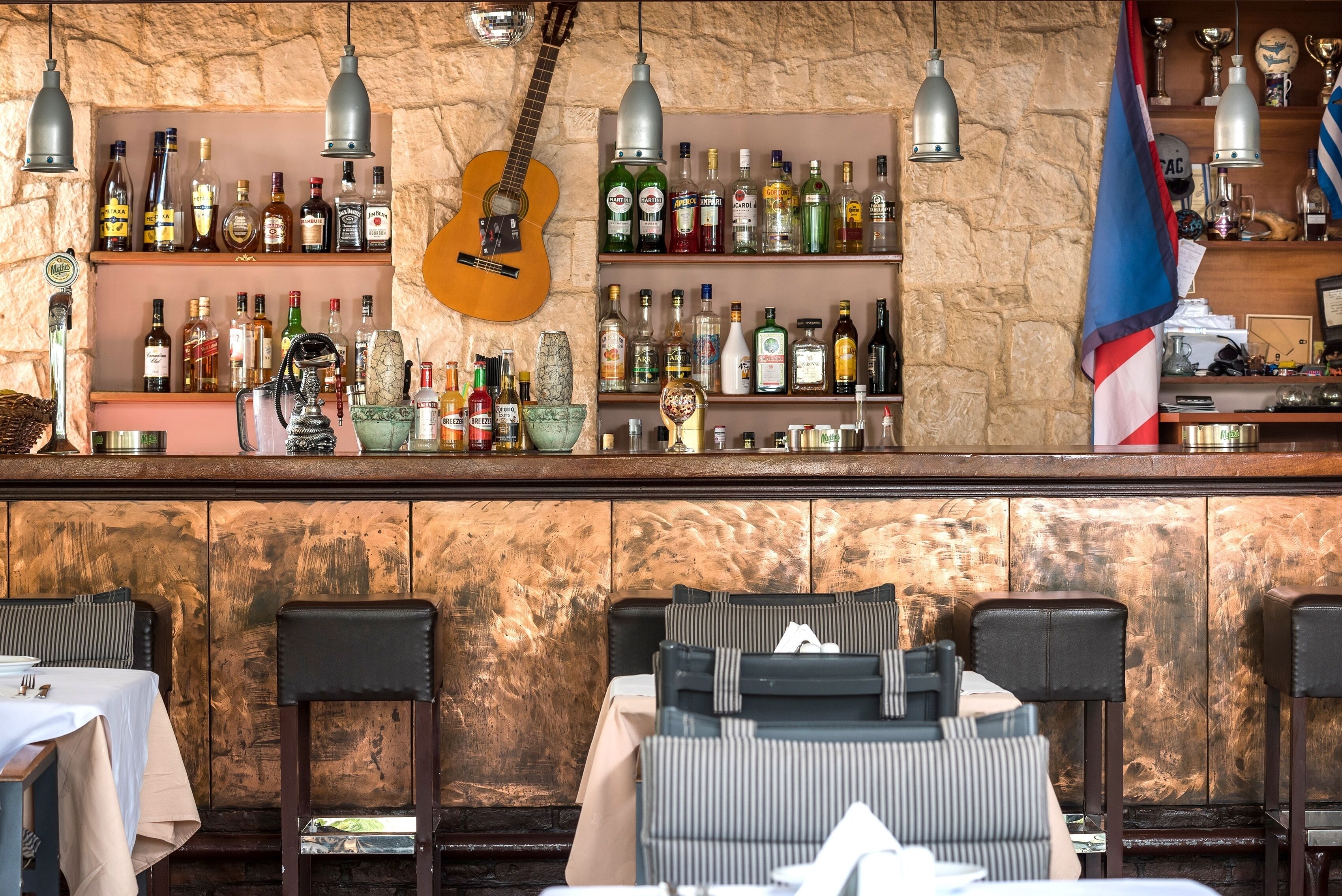 A bar area with a variety of liquor bottles, a guitar, and a flag.