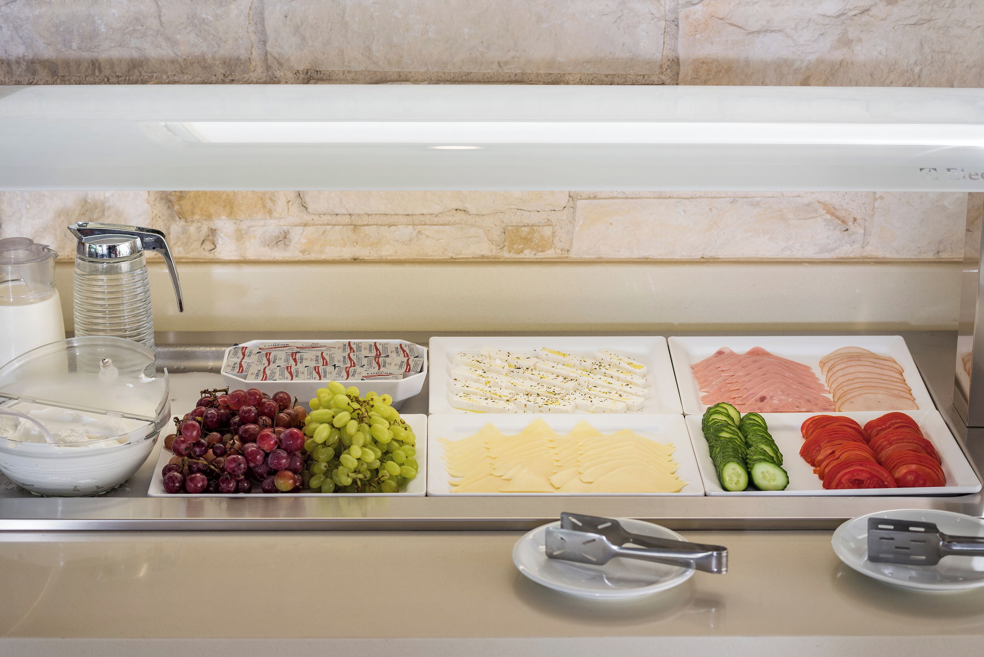 A buffet spread with various food items including grapes, cheese, and sliced meats.