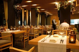 A restaurant with wooden tables and chairs, white tablecloths, and floral decorations.