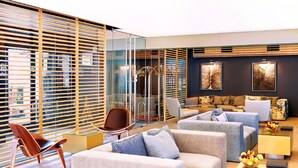 Un moderno vestíbulo de hotel con zona de estar, separador de vidrio y obras de arte en las paredes.