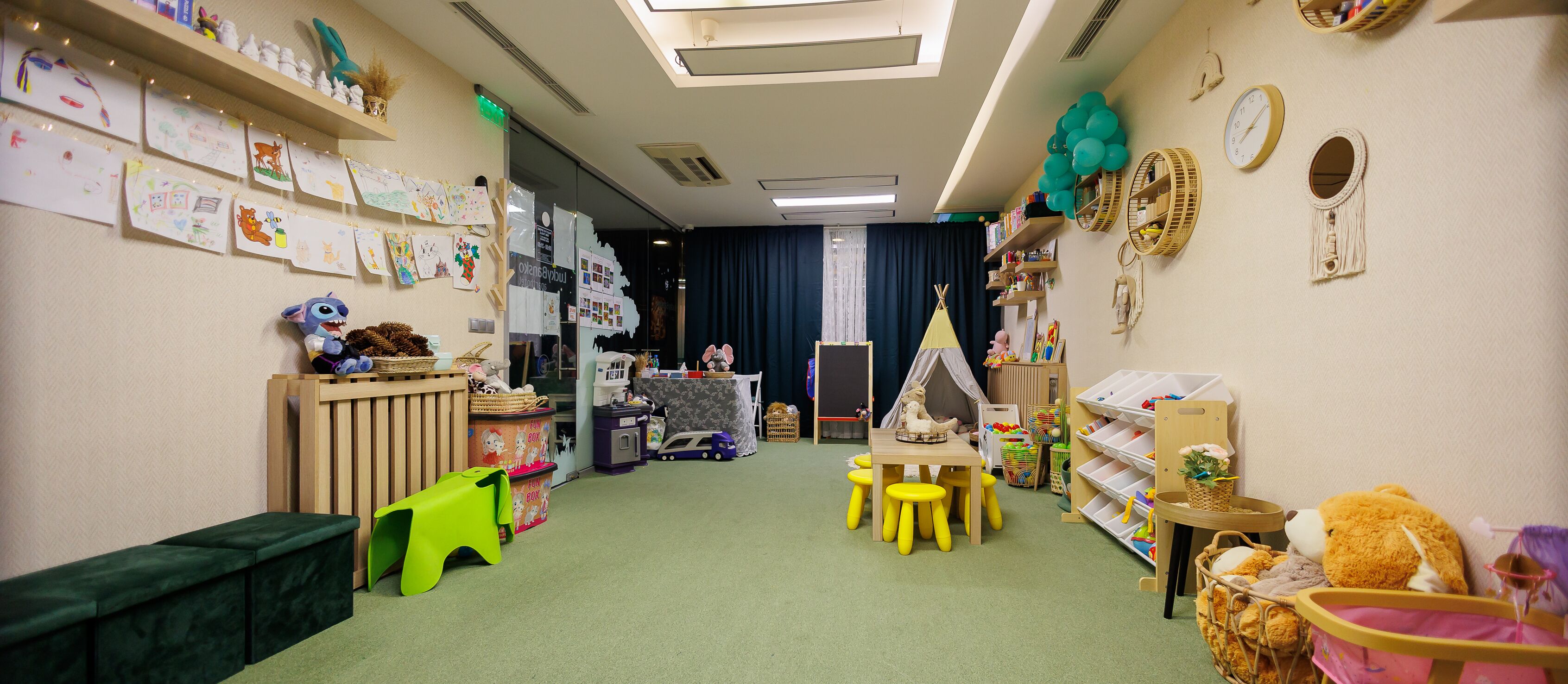 A children's playroom with a play table, chairs, and various toys and decorations.