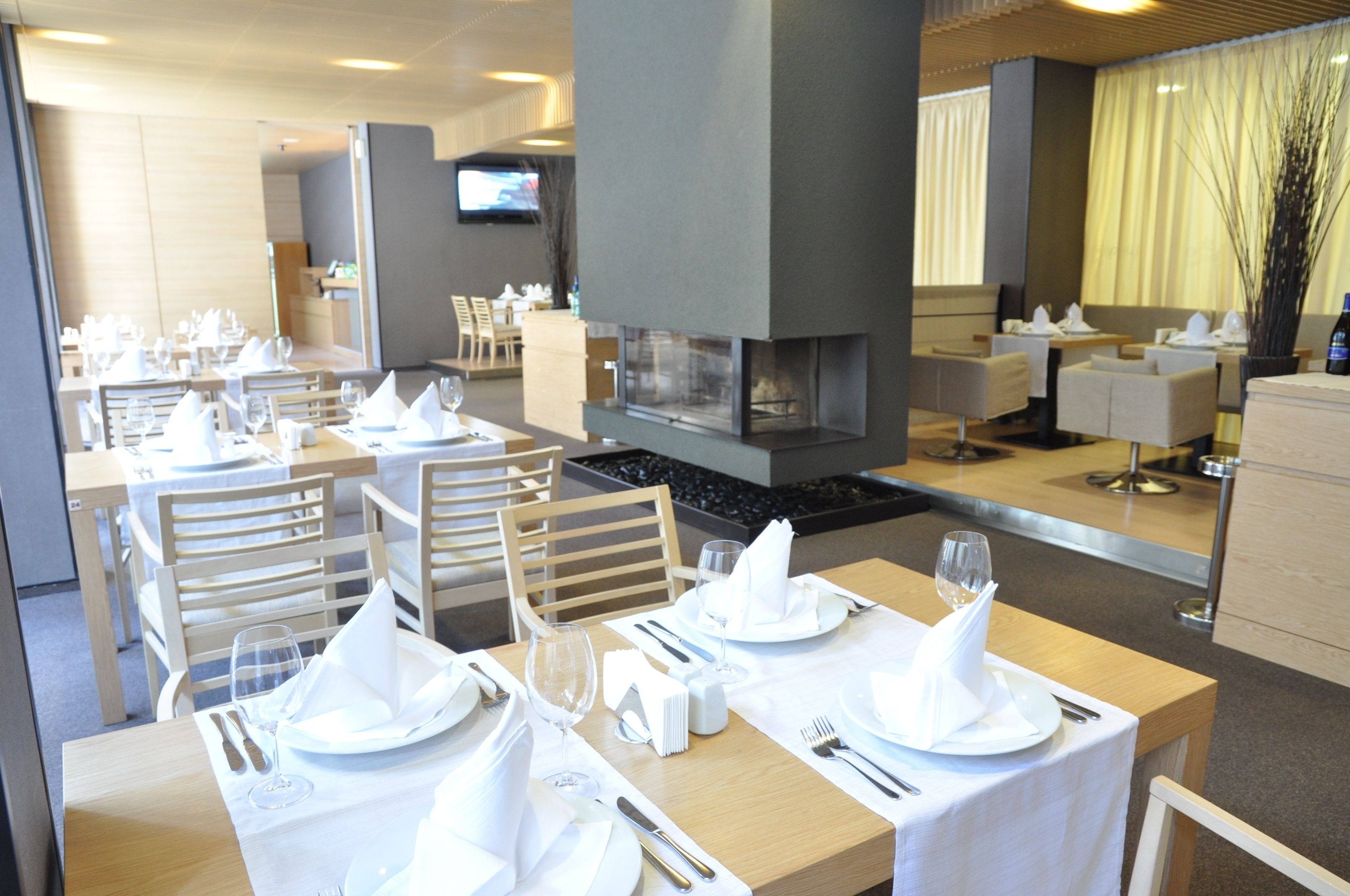 A restaurant with neatly set tables, a fireplace, and a television in the background.