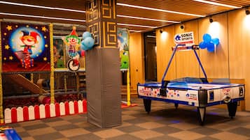 A children's play area with a pool table, inflatable bounce house, and a clown-themed backdrop.