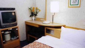 Habitación de hotel con una cama, un escritorio con teléfono, televisión y un armario pequeño.