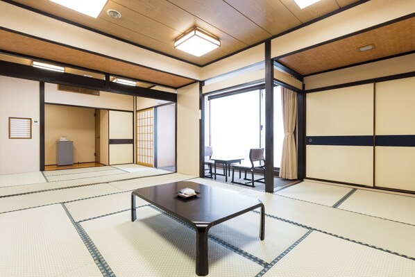 Una habitación tradicional japonesa con suelo de tatami, una mesa baja y puertas correderas.