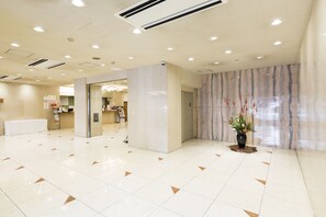 Eine großzügige Lobby mit Marmorwand, einer Rezeption und einer Zimmerpflanze.