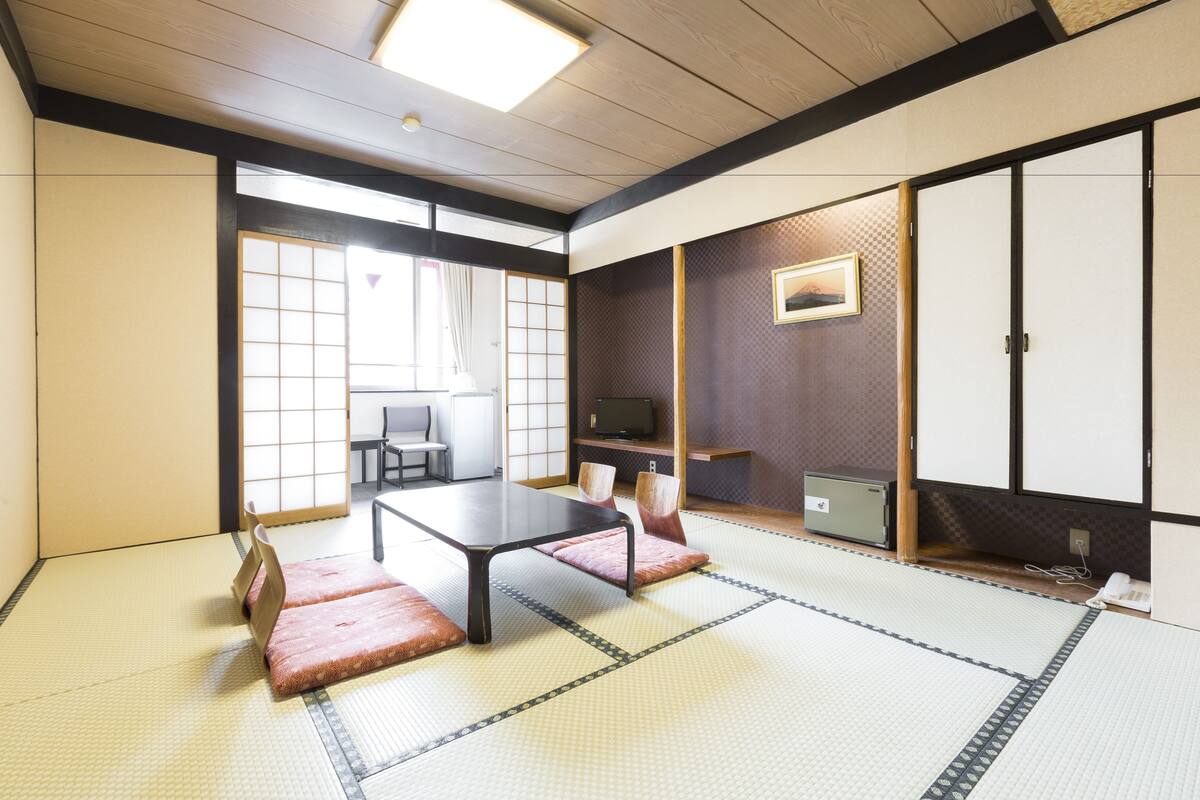 Ein traditioneller japanischer Raum mit Tatami-Bodenbelag, einem niedrigen Tisch und gleitenden Türen.