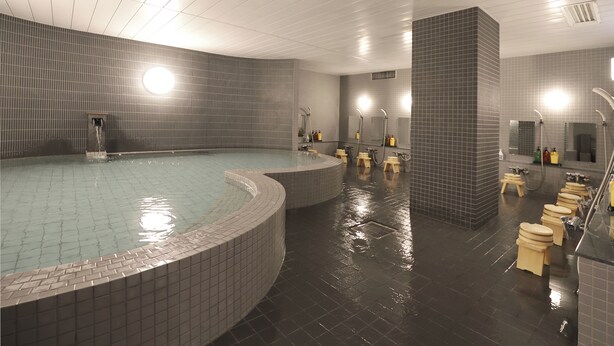 A modern indoor pool with a curved design, surrounded by wooden stools and a row of toilets. - Kyoto Hotel SANOYA (Kyoto)