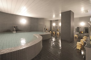 Una piscina interior moderna con diseño curvo, rodeada de taburetes de madera y una fila de inodoros.