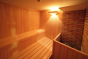 Eine Holzsauna mit einer Bank und einer Ziegelwand.