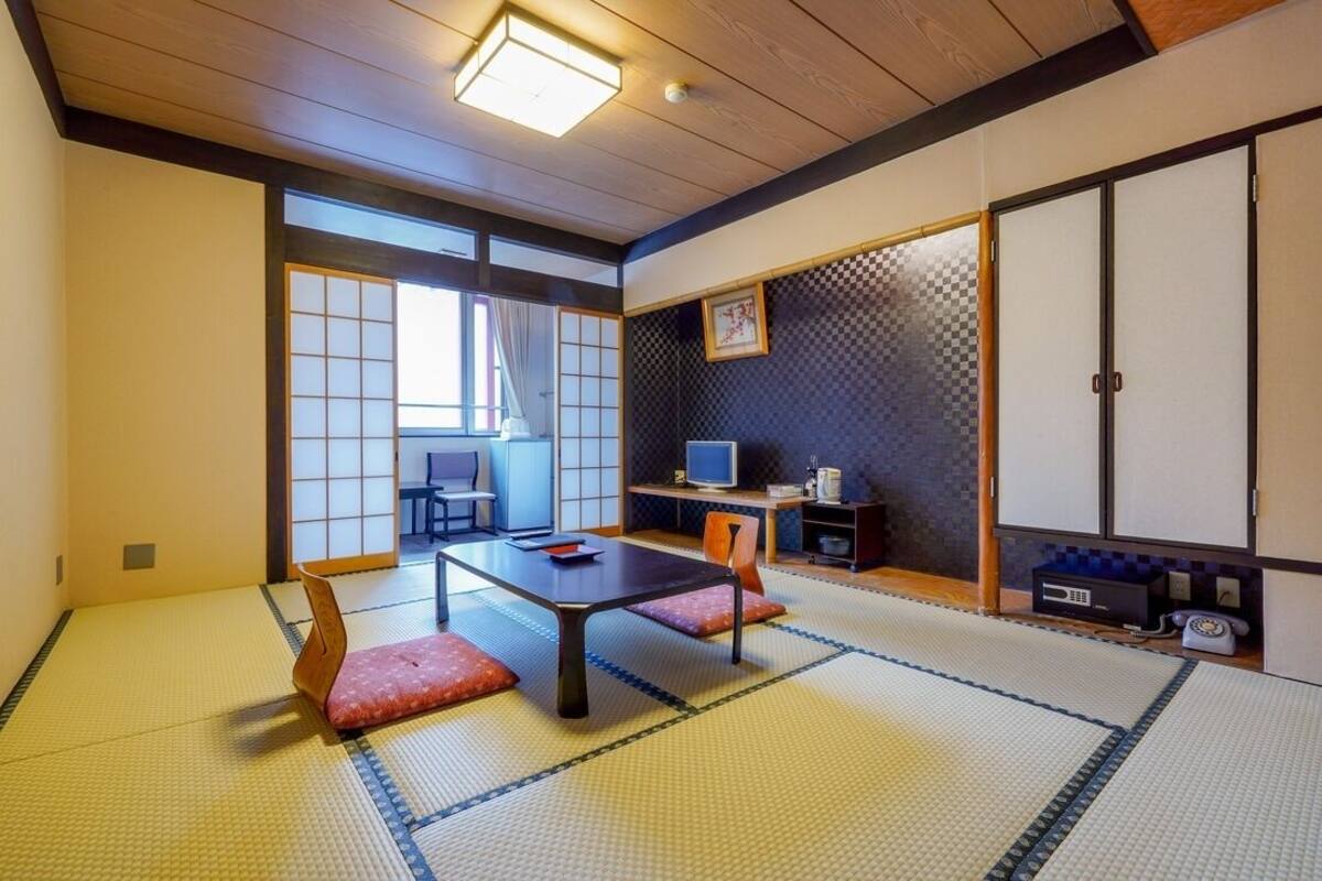 Ein traditioneller japanischer Raum mit Tatami-Bodenbelag, einem niedrigen Tisch und Schiebetüren.