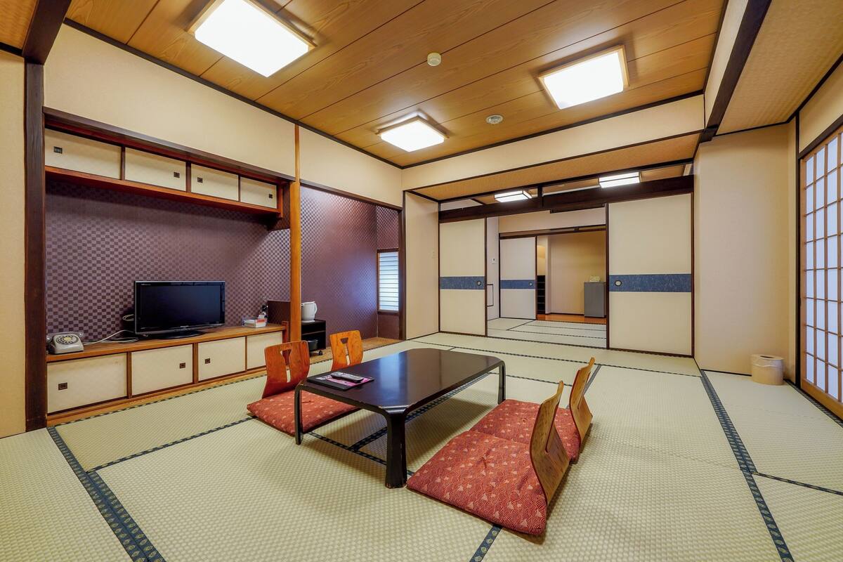 Ein traditioneller japanischer Raum mit Tatami-Böden, einem niedrigen Tisch und Kissen.