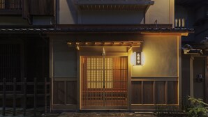 Un edificio japonés tradicional con una puerta de madera, un balcón y un pequeño jardín.