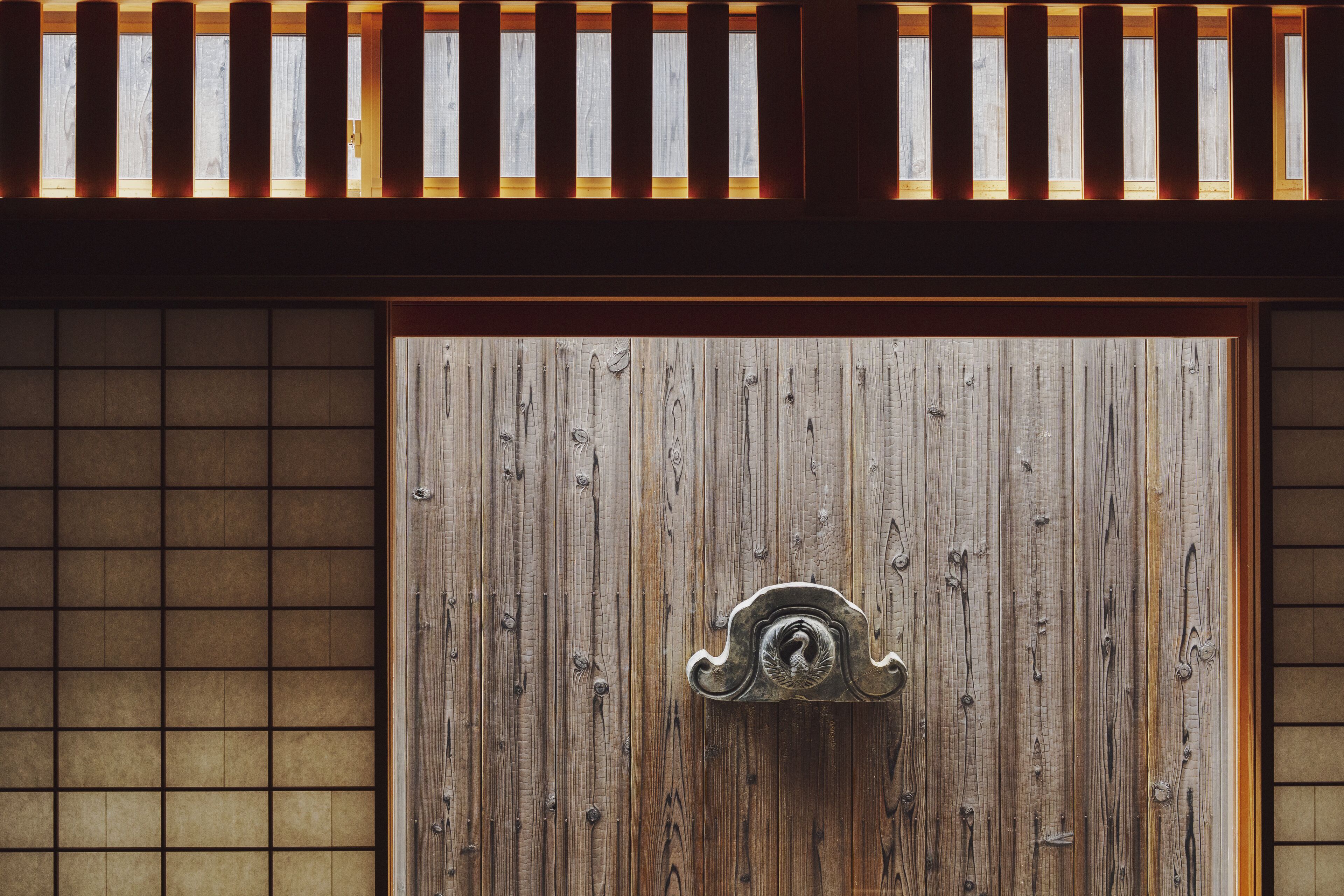 A wooden door with a metal handle and a decorative panel above it.