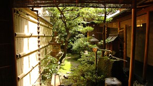 Un jardín japonés tradicional con bambú, un pequeño estanque y faroles de piedra.