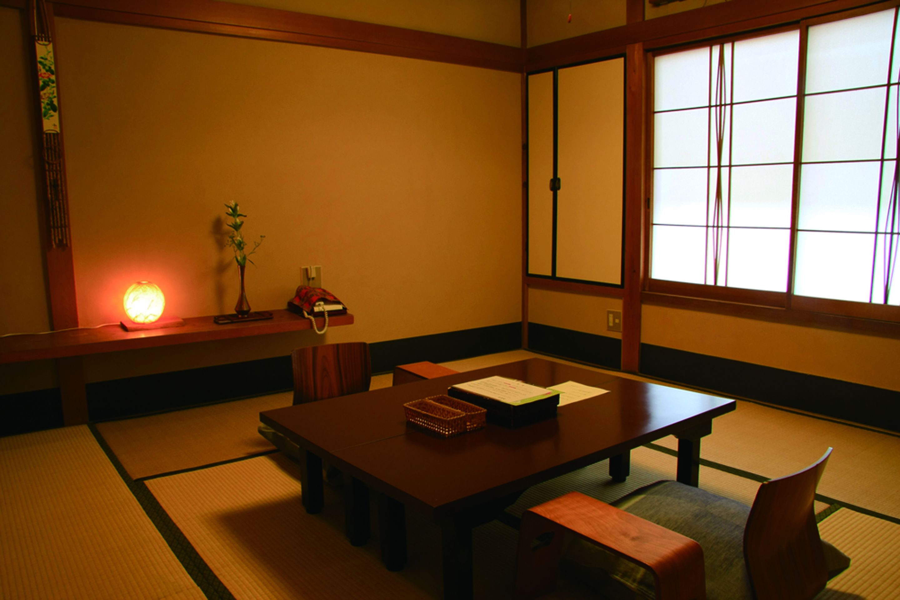 A traditional Japanese tatami room with a low table, cushions, and a shoji screen.