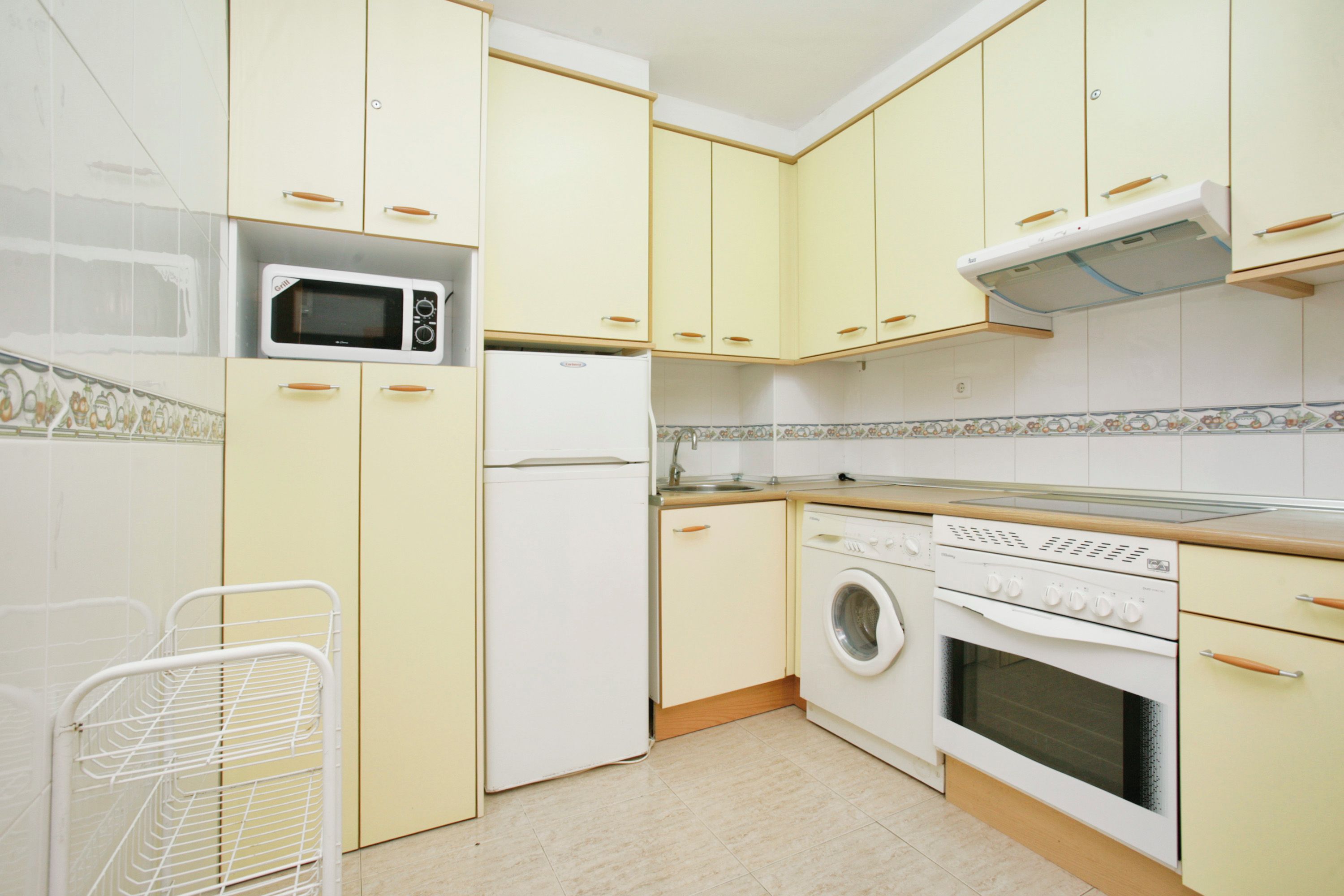 A kitchen with a microwave, refrigerator, washing machine, and stove.