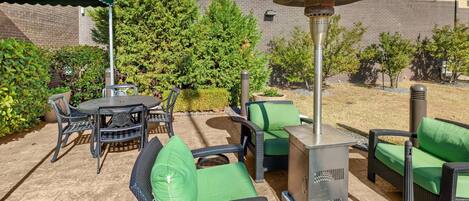 An outdoor patio area with wicker furniture, a table, and a grill.