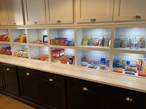 Una cocina con estantes abiertos, llena de provisiones, salsas y utensilios de cocina.