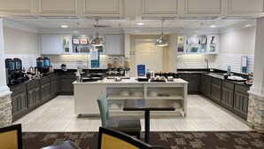 Una cocina moderna con una isla central, muebles oscuros y una alfombra estampada.