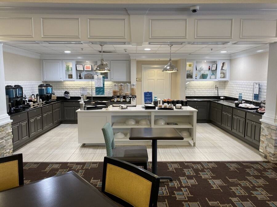 Une cuisine moderne dotée d’un îlot central, de meubles de couleur sombre et d’un tapis à motifs.