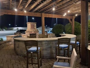 An outdoor patio area with a stone fireplace, seating, and a view of a parking lot at night.