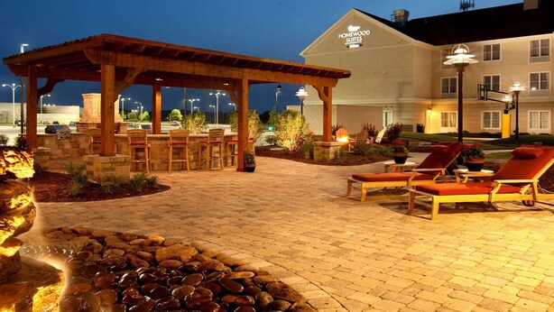 Un patio de hotel con mobiliario exterior, una fuente de agua y un área de descanso junto a la piscina.