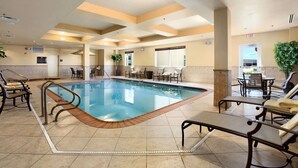 Una piscina interior con sillas de descanso y un comedor.
