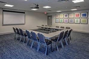 A conference room with a long table, chairs, a projector screen, and framed artwork on the walls. - Holiday Inn Express & Suites Smyrna by IHG (Smyrna)