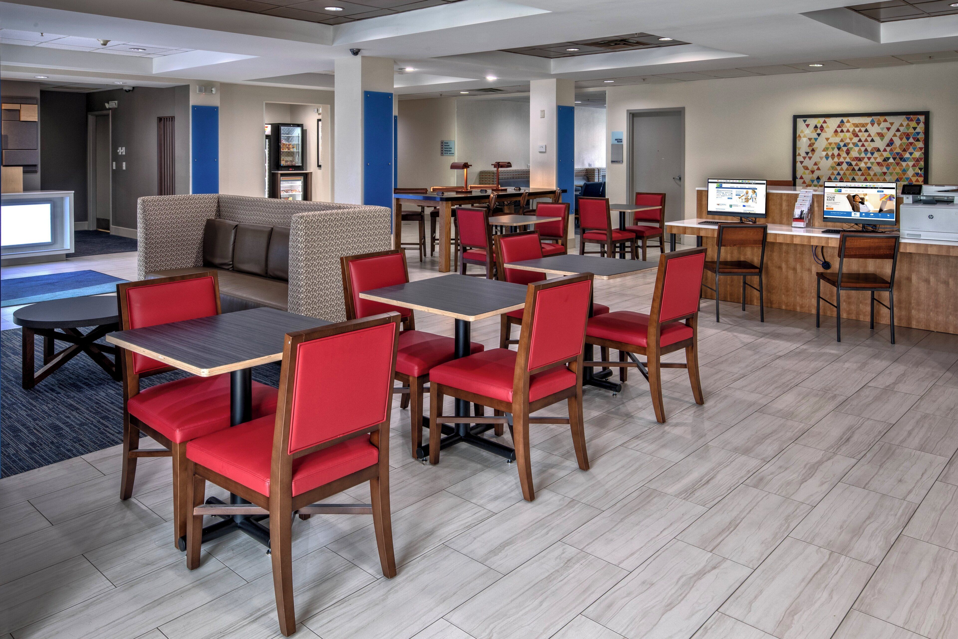 A hotel lobby with seating areas, a reception desk, and a computer station.