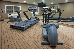 A gym with multiple treadmills, stationary bikes, and a rowing machine.
