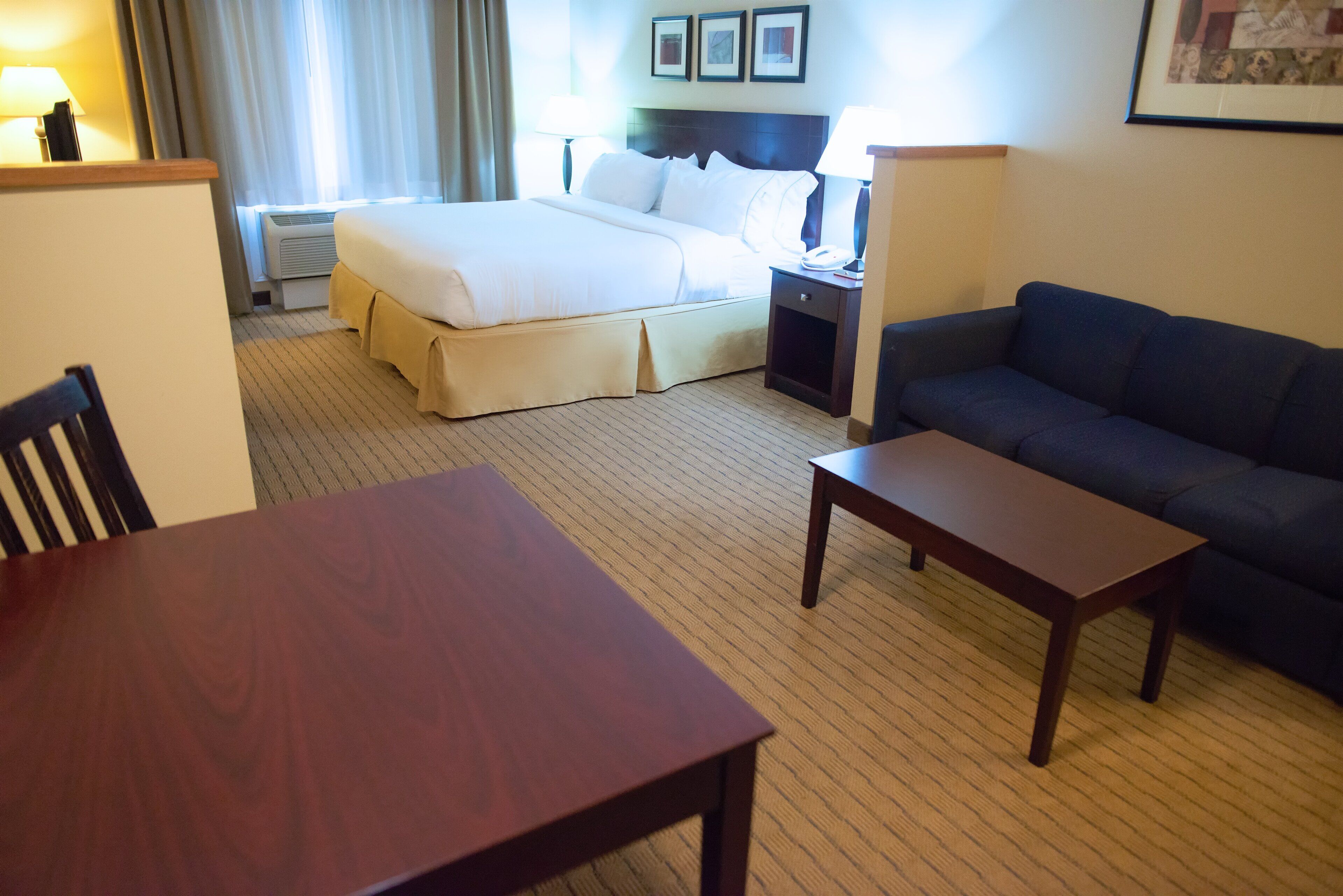Una habitación de hotel con una cama, un sofá, una mesa y una mesita de noche.