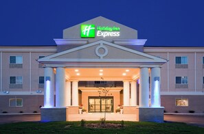 A Holiday Inn Express building with a central entrance, large columns, and a prominent green logo. - Holiday Inn Express Devils Lake by IHG (Devils Lake)