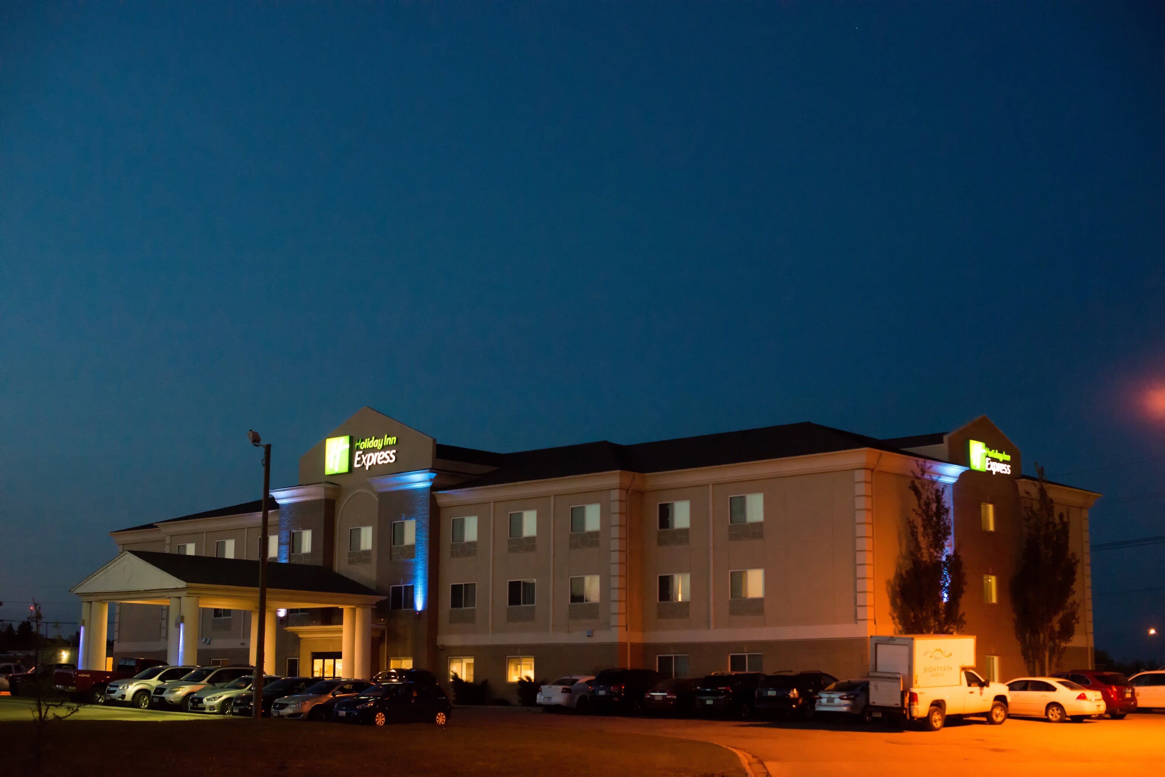 A Holiday Inn Express hotel with a parking lot and several cars.