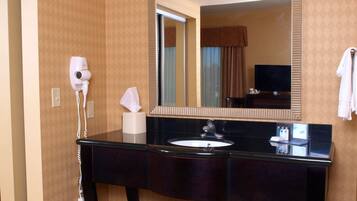 A bathroom with a large mirror, vanity, and a hairdryer.