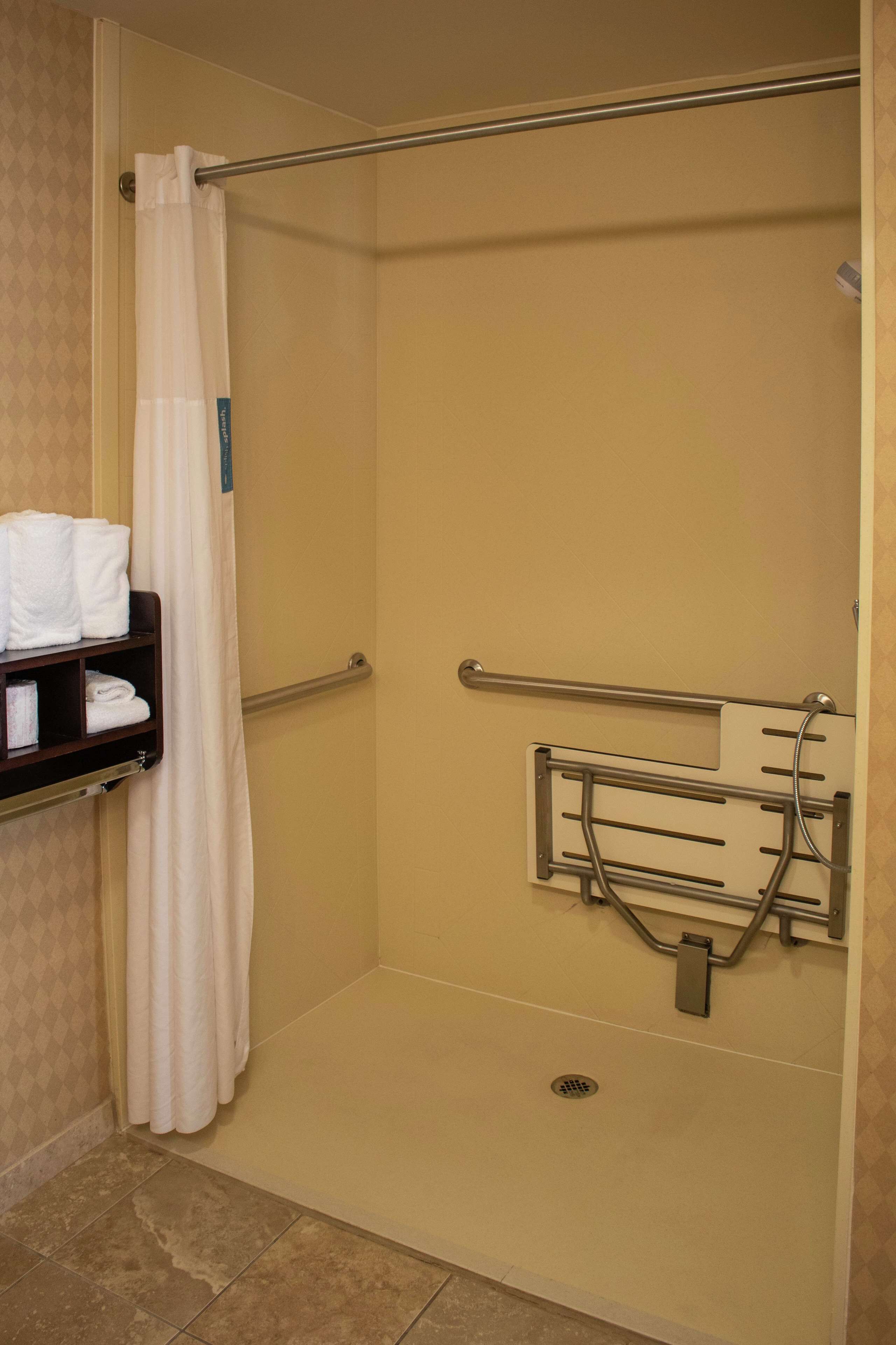 A shower area with a grab bar, a towel rack, and a shower curtain.