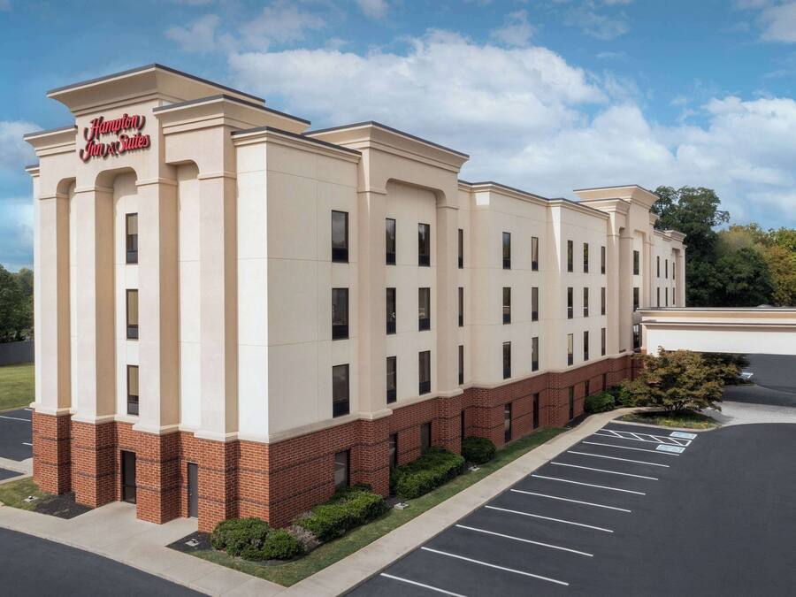 Un hotel Hampton Inn & Suites con fachada de ladrillo, varias ventanas y un estacionamiento.