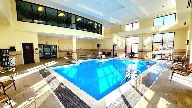 A large indoor swimming pool with a sunlit floor, a reception desk, and a seating area with chairs. - Hampton Inn & Suites Chesapeake-Battlefield Blvd. (Chesapeake)